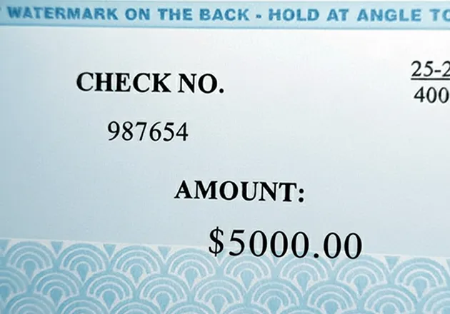 Close-up of a settlement check showing the amount line and the watermark notice printed along the top edge