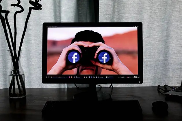 Facebook logos shown as binocular lenses on a monitor, illustrating the class action alleging Meta profited from scam ads