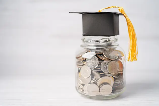 A graduation cap on a jar of coins — the borrower-defense class action settlement cancelling about $23 billion in federal student loans
